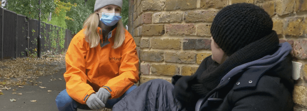 lady speaking with person sleeping on the street
